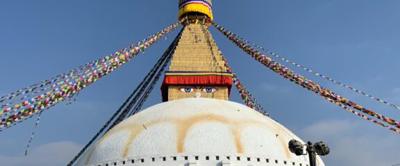 Boudha Nath Stupa, a UNESCO World Heritage Site in Kathmandu, Nepal, adorned with prayer flags and surrounded by prayer wheels.
