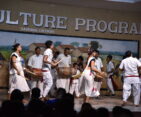 Tharu people dancing and playing music in traditional costumes, expressing their culture.