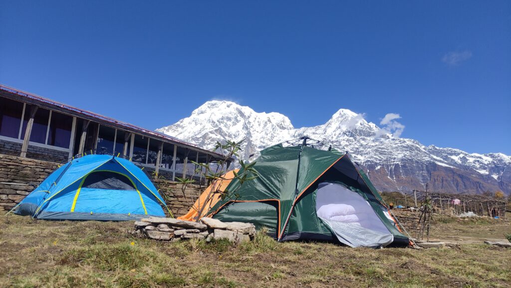 Tent pitched against a backdrop of towering mountains, offering a picturesque camping experience in the wilderness.