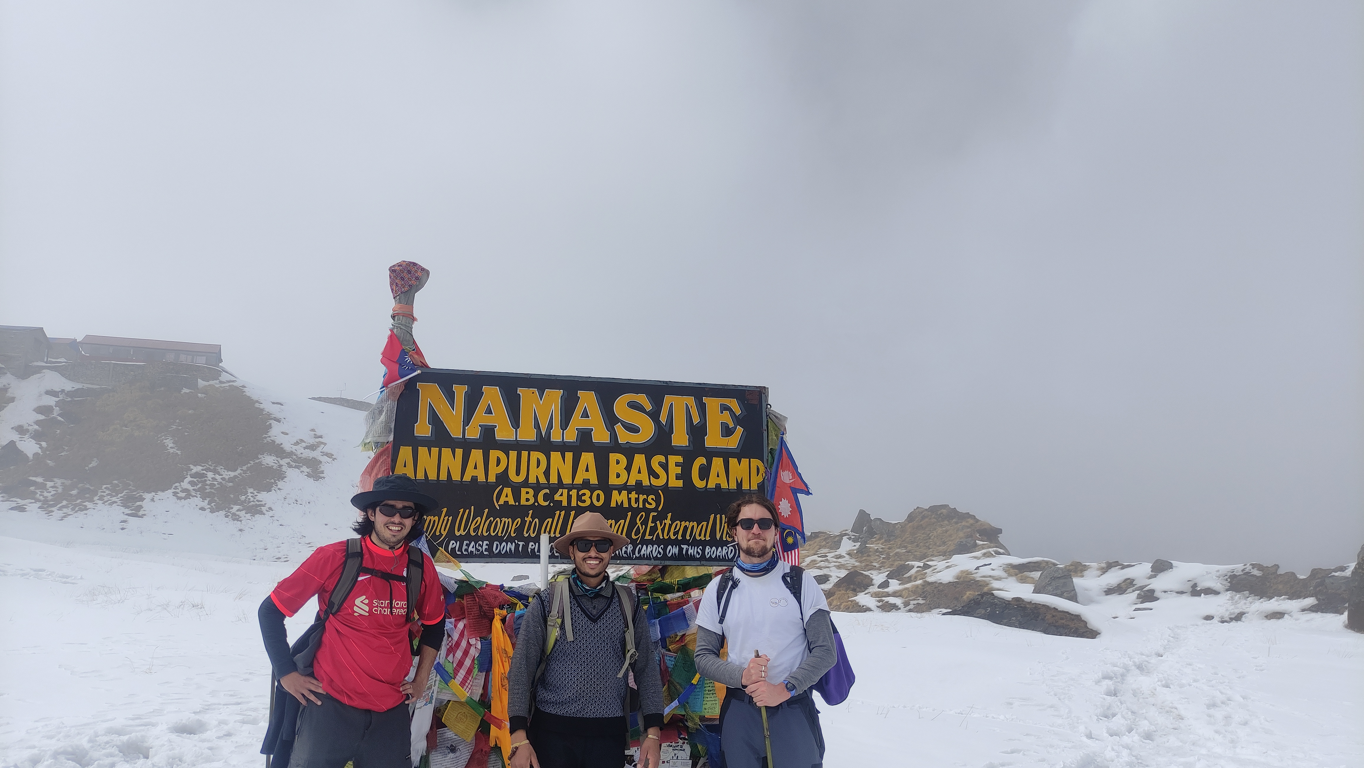 Arrival at Annapurna Base Camp, with trekkers and guides celebrating the accomplishment amidst towering mountain peaks.