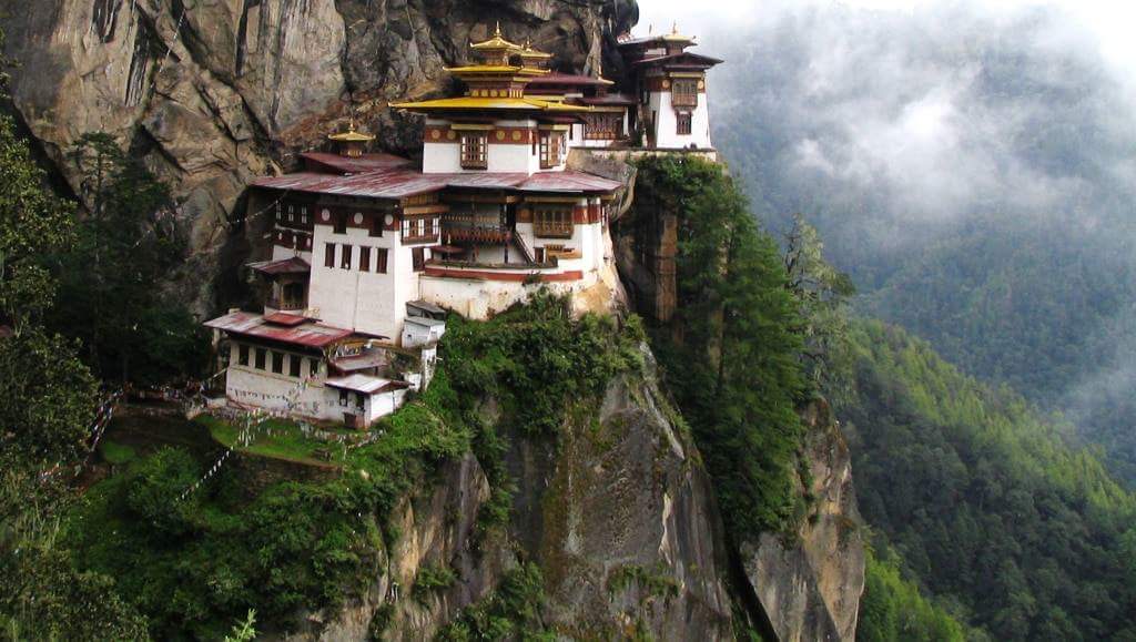 Tiger's Nest Monastery (Paro Taktsang), Bhutan, perched on a cliffside surrounded by lush greenery and overlooking the valley below.