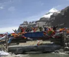 Pilgrimage group celebrating on a prayer flag bridge with Mount Kailash during Kailash Mansarovar Yatra 2026