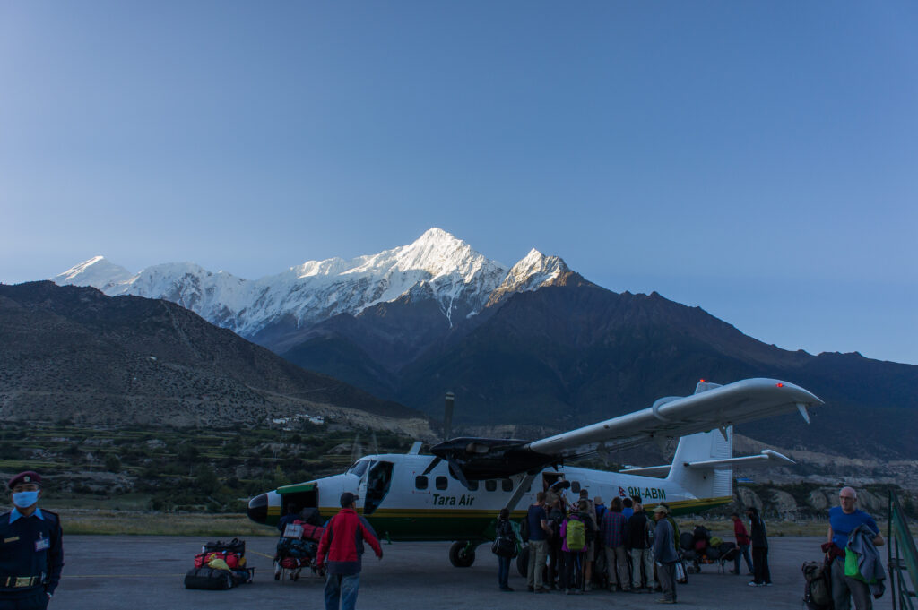 Aircraft parked on the runway at Jomsom Airport with mountain views in the background.