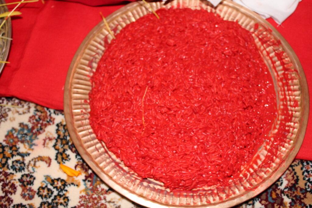 Tika: A close-up of an elder applying tika, a red mixture of rice, yogurt, and vermilion, on a younger family member's forehead during Dashain.