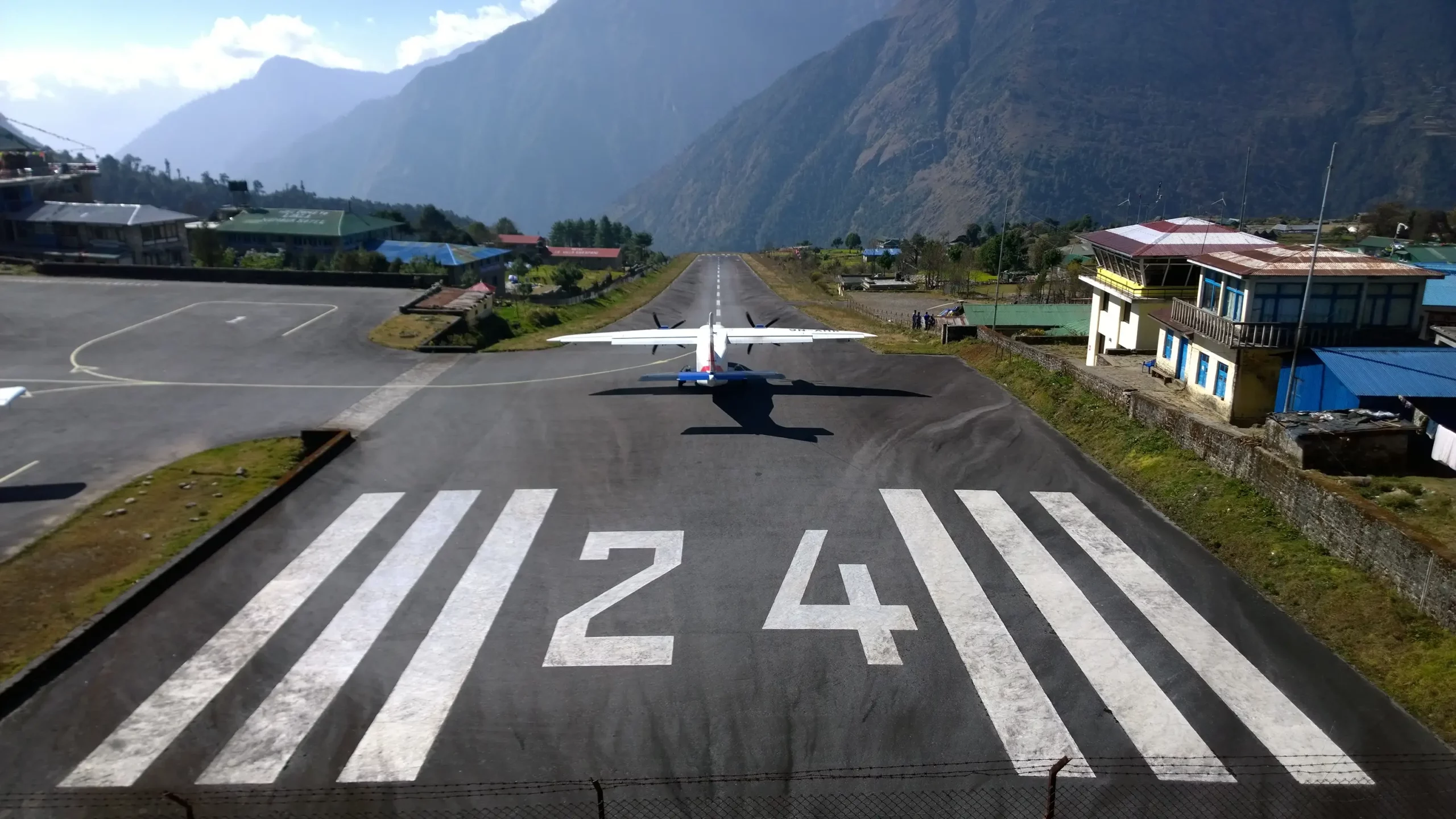 An iconic aerial view of Lukla Airport, the gateway to Everest Base Camp, nestled in the Himalayan mountains.