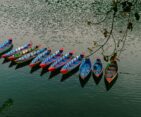 Traditional colorful wooden boats floating on Phewa Lake in Pokhara, Nepal