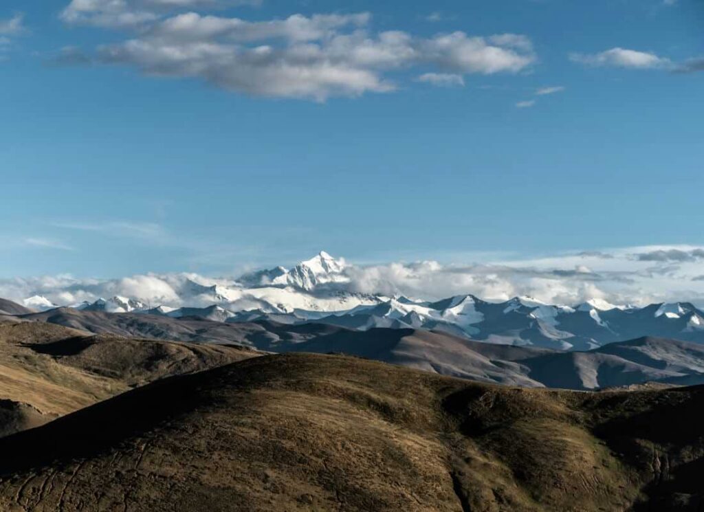 Majestic Himalayan range in Tibet, featuring snow-capped peaks under a clear blue sky, offering breathtaking views of serene and rugged landscapes.