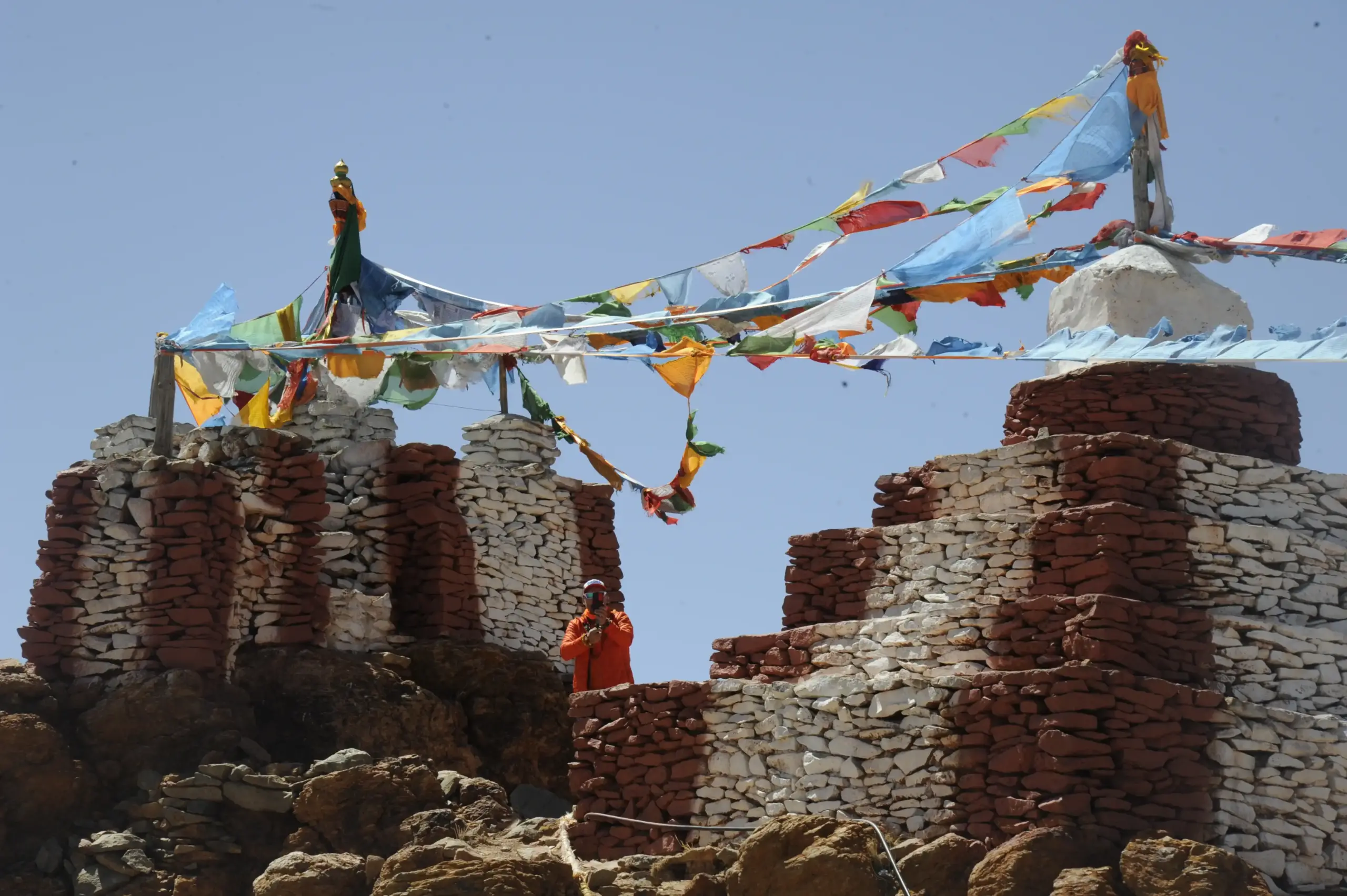 Colorful Tibetan prayer flags above ancient stone structures near Chiu Gompa during Kailash Mansarovar Yatra