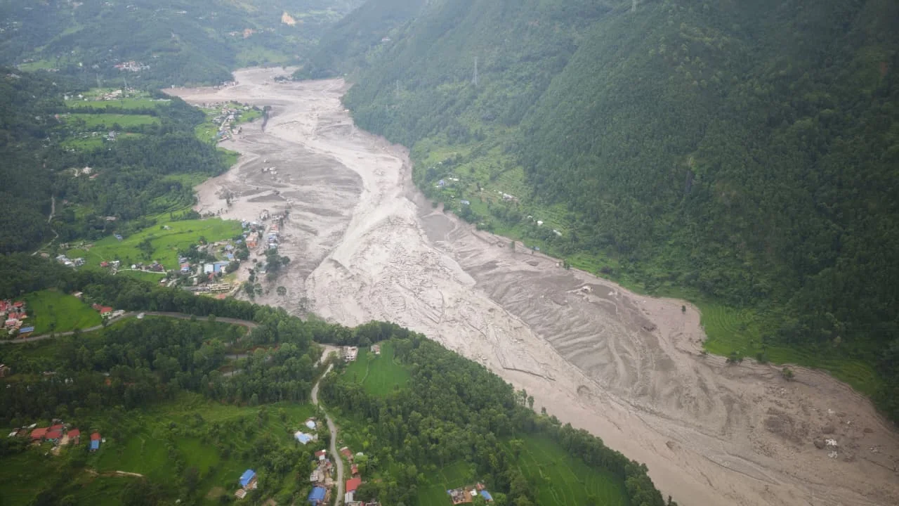 Aerial view showing the devastating impact of the 2026 Bhotekoshi flood, with mud, rocks, and debris covering large areas around homes and local infrastructure.